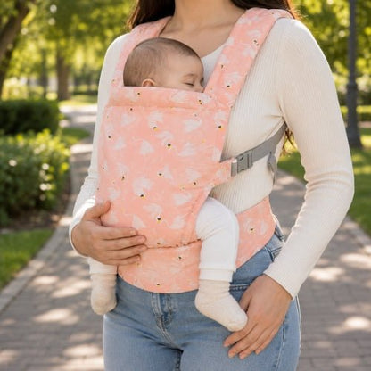 Porte bebe preforme rose imprimé porté devant dans un parc, vue de face