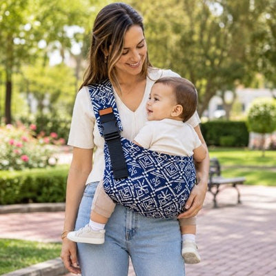 Porte-bébé souple à une épaule bleu à motif géométrique avec boucle réglable, port latéral dans un parc