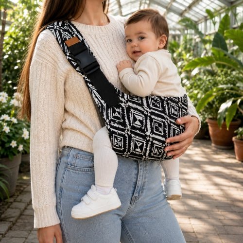Porte-bébé souple à une épaule noir et blanc à motif géométrique, port latéral dans une serre
