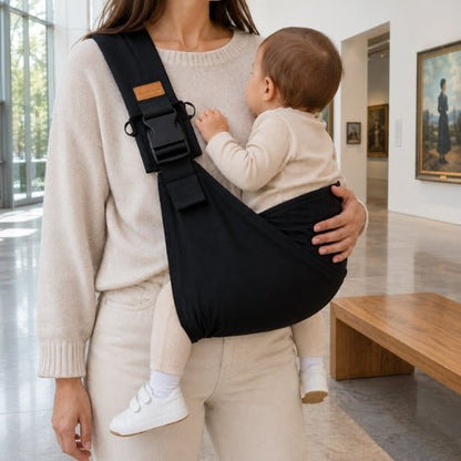 Porte-bébé souple à une épaule noir avec boucle réglable, port latéral dans un musée
