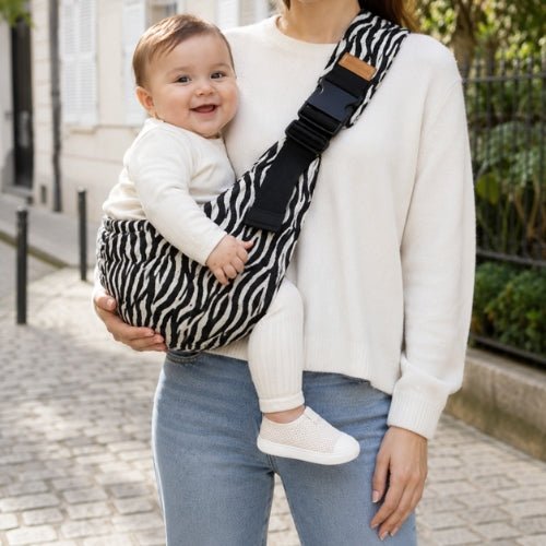Porte-bébé souple à une épaule motif zébré noir et blanc avec boucle réglable, port latéral dans une rue