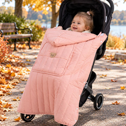 Protège porte-bébé doudoune rose installé sur une poussette, avec bébé au visage visible, capuche repliée et poche frontale à motif ours