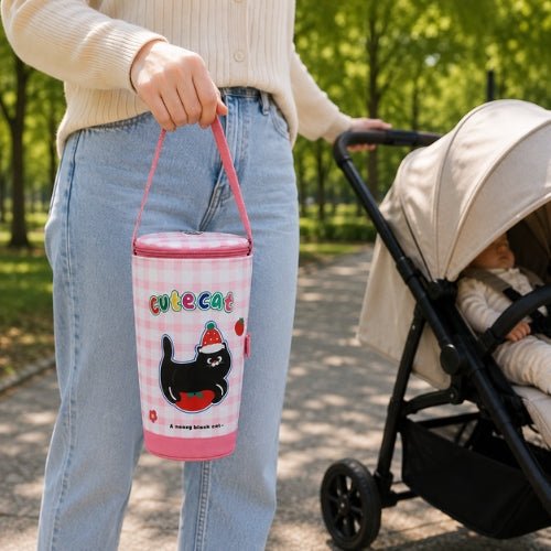 Sac à carreaux pour biberon à motif chat porté par sa poignée près d’une poussette