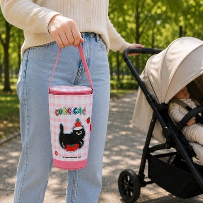 Sac à carreaux pour biberon à motif chat porté par sa poignée près d’une poussette
