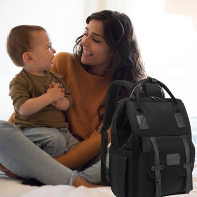 Une maman souriante avec son bébé et le sac à dos à langer NoirEssentiel noir, pratique et confortable pour les parents actifs