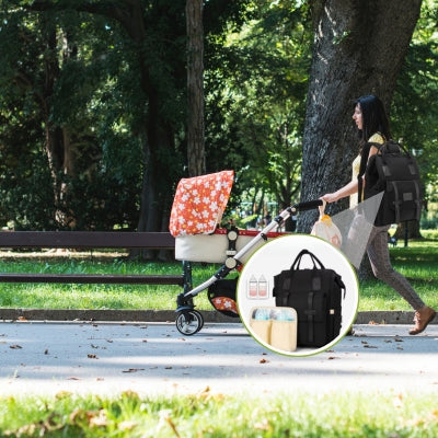 Femme poussant une poussette avec un sac à dos à langer NoirEssentiel noir attaché, affichant des poches multiples pour un rangement optimal