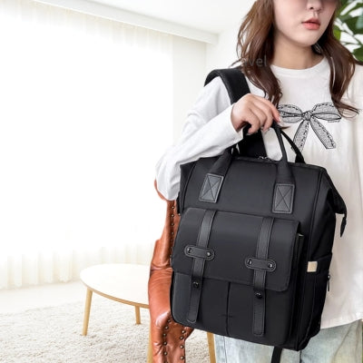 Femme portant un sac à dos à langer NoirEssentiel noir au design moderne et élégant, parfait pour les sorties quotidiennes