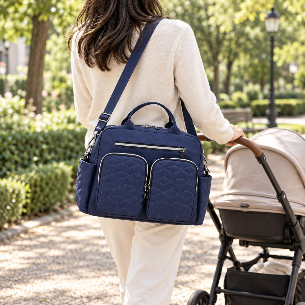 Sac à langer Double poche avant Bleu foncé porté en bandoulière près d’une poussette