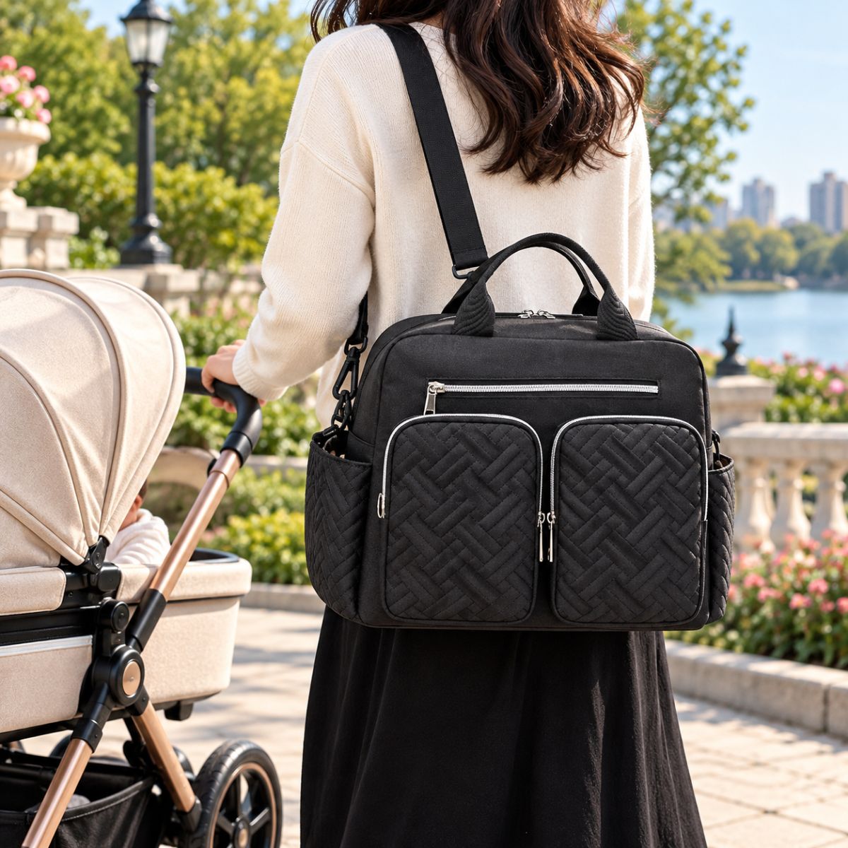 Sac à langer Double poche avant Noir porté en bandoulière près d’une poussette