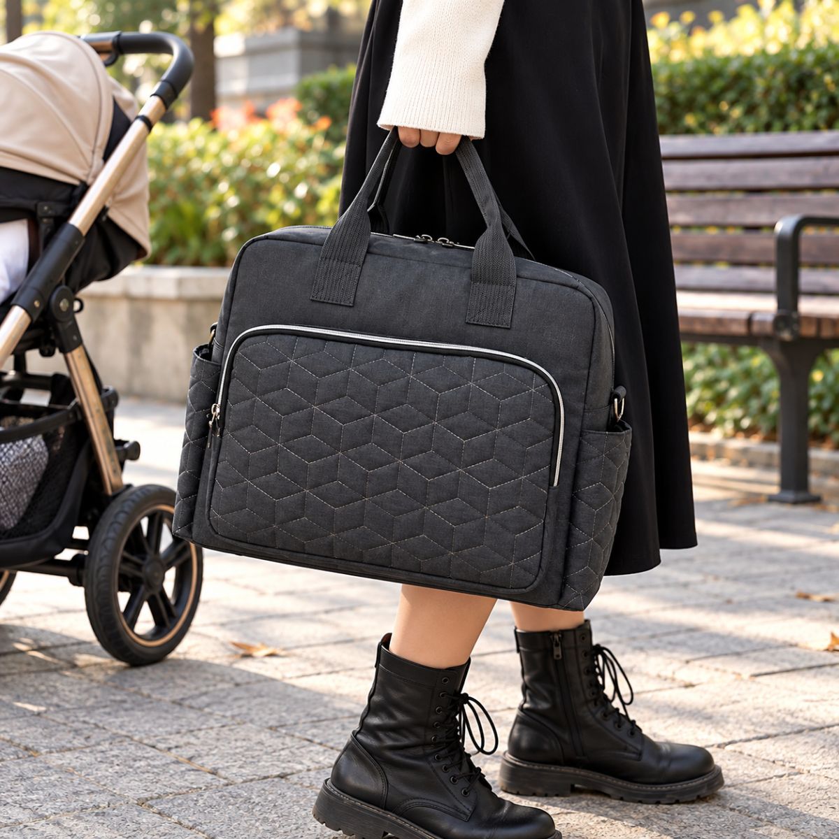 Sac à langer Grande poche avant Noir porté à la main près d’une poussette