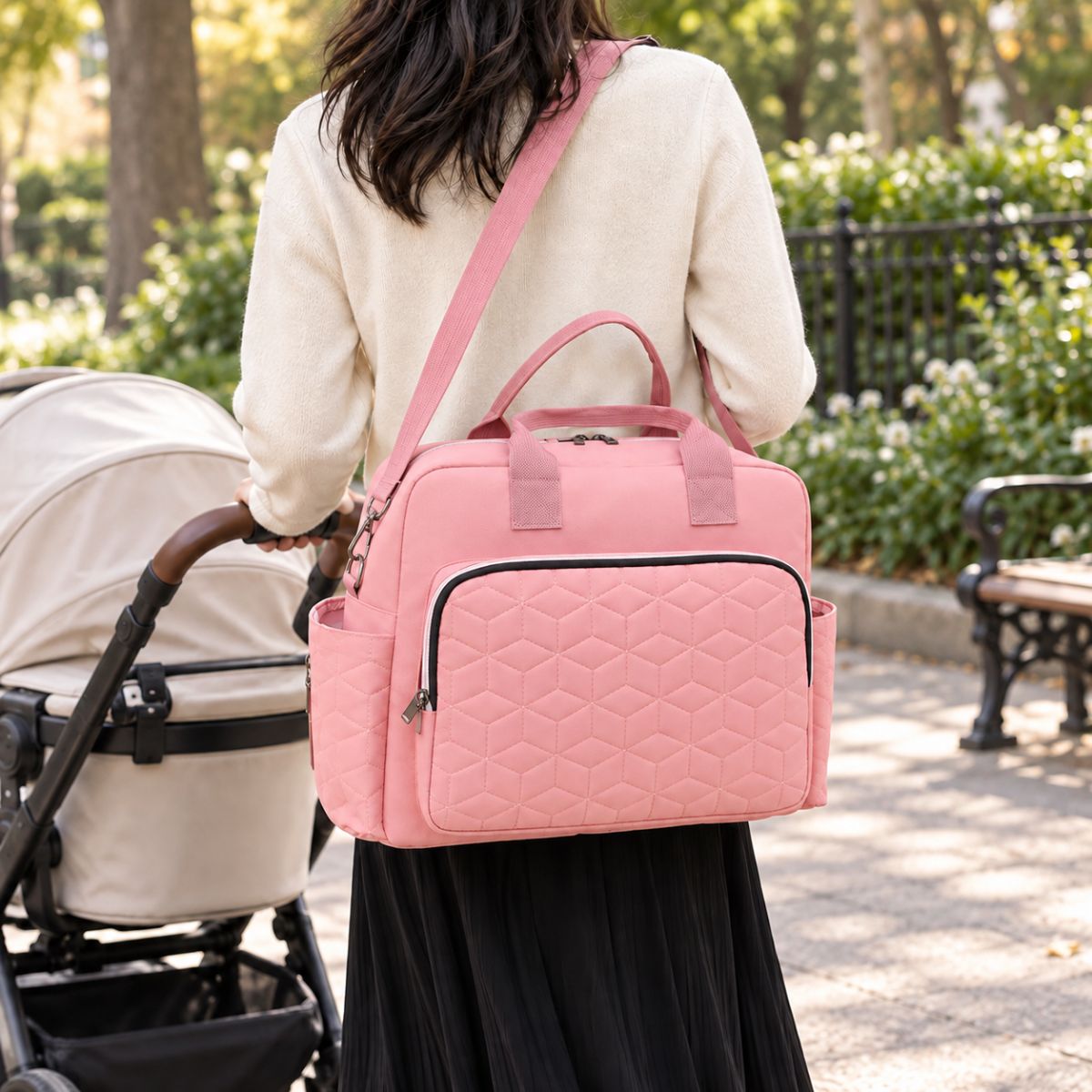 Sac à langer Grande poche avant Rose porté en bandoulière pendant une promenade