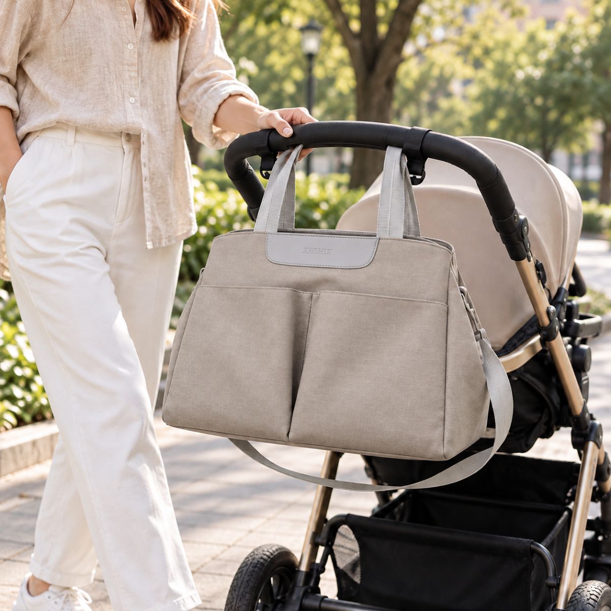 Sac à langer avec tapis de change gris clair présenté avec une poussette en extérieur