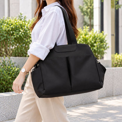 Sac à langer avec tapis de change noir porté à l’épaule en extérieur