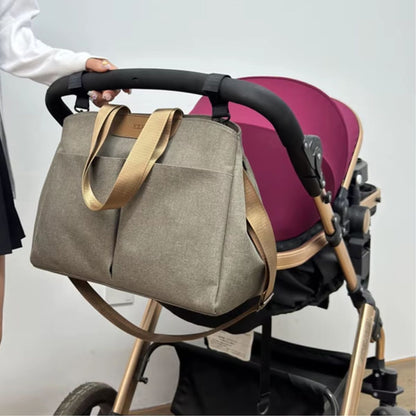 Sac à langer avec tapis de change taupe installé près d’une poussette