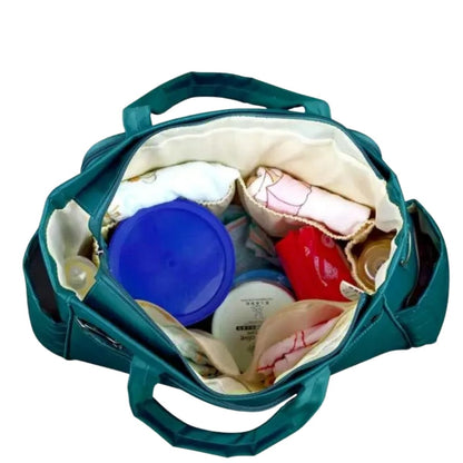 Sac a langer avec tapis de change vert paon, vue intérieure avec compartiments remplis d’accessoires bébé