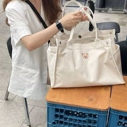 Sac a langer bebe beige porté à la main par une maman en extérieur