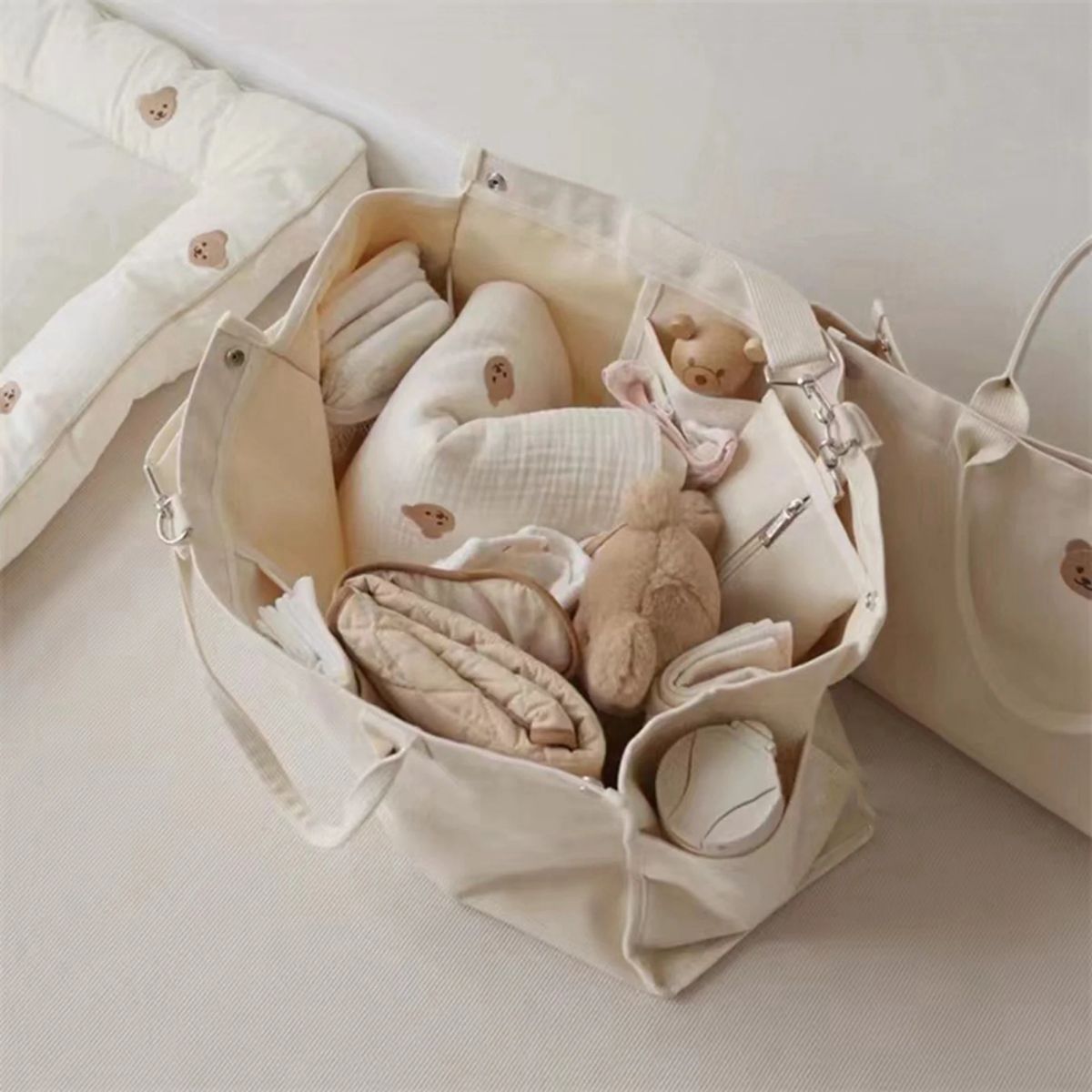 Sac a langer bebe beige vu de dessus, compartiments remplis de jouets et textiles