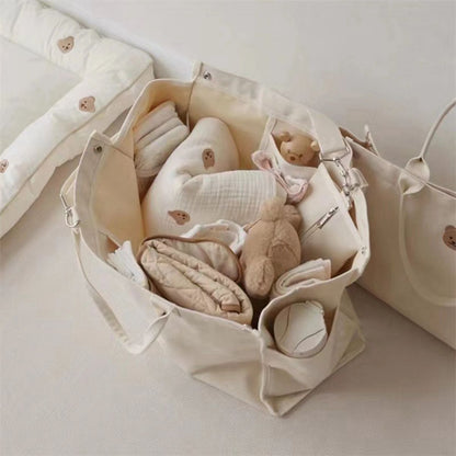 Sac a langer bebe beige vu de dessus, compartiments remplis de jouets et textiles