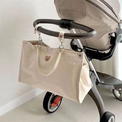 Sac a langer bebe accroché à une poussette grâce aux attaches universelles