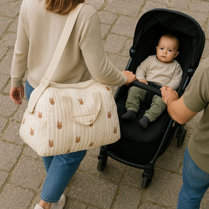 sac a langer bebe lapins brodés porté à l’épaule par un parent marchant derrière une poussette