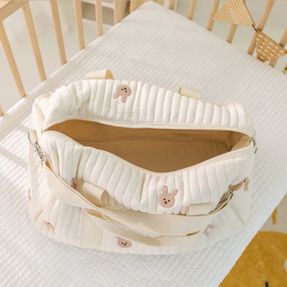 sac a langer bebe lapins brodés ouvert, intérieur beige, posé dans un lit bébé