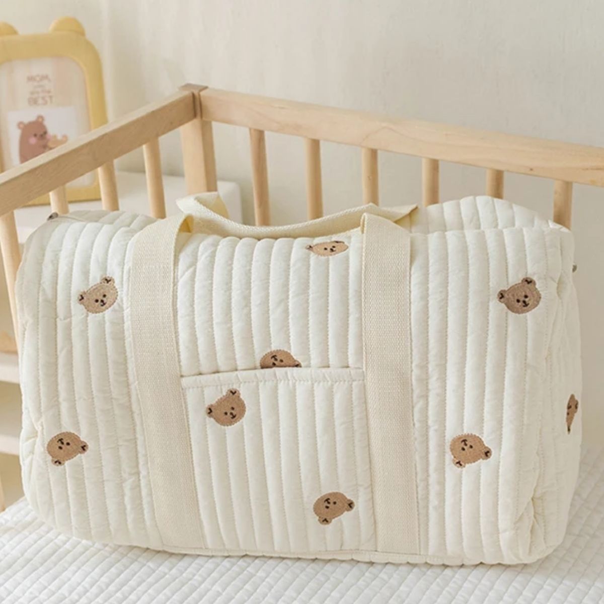 sac a langer bebe oursons brodés posé dans un lit à barreaux en bois clair