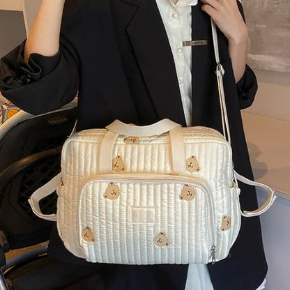 Femme portant le sac a langer ourson en bandoulière, modèle crème doux et compact