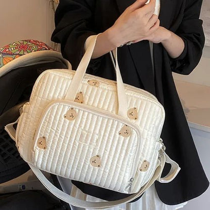 Vue de face d’un sac a langer à oursons, tenu à la main par une femme habillée en noir