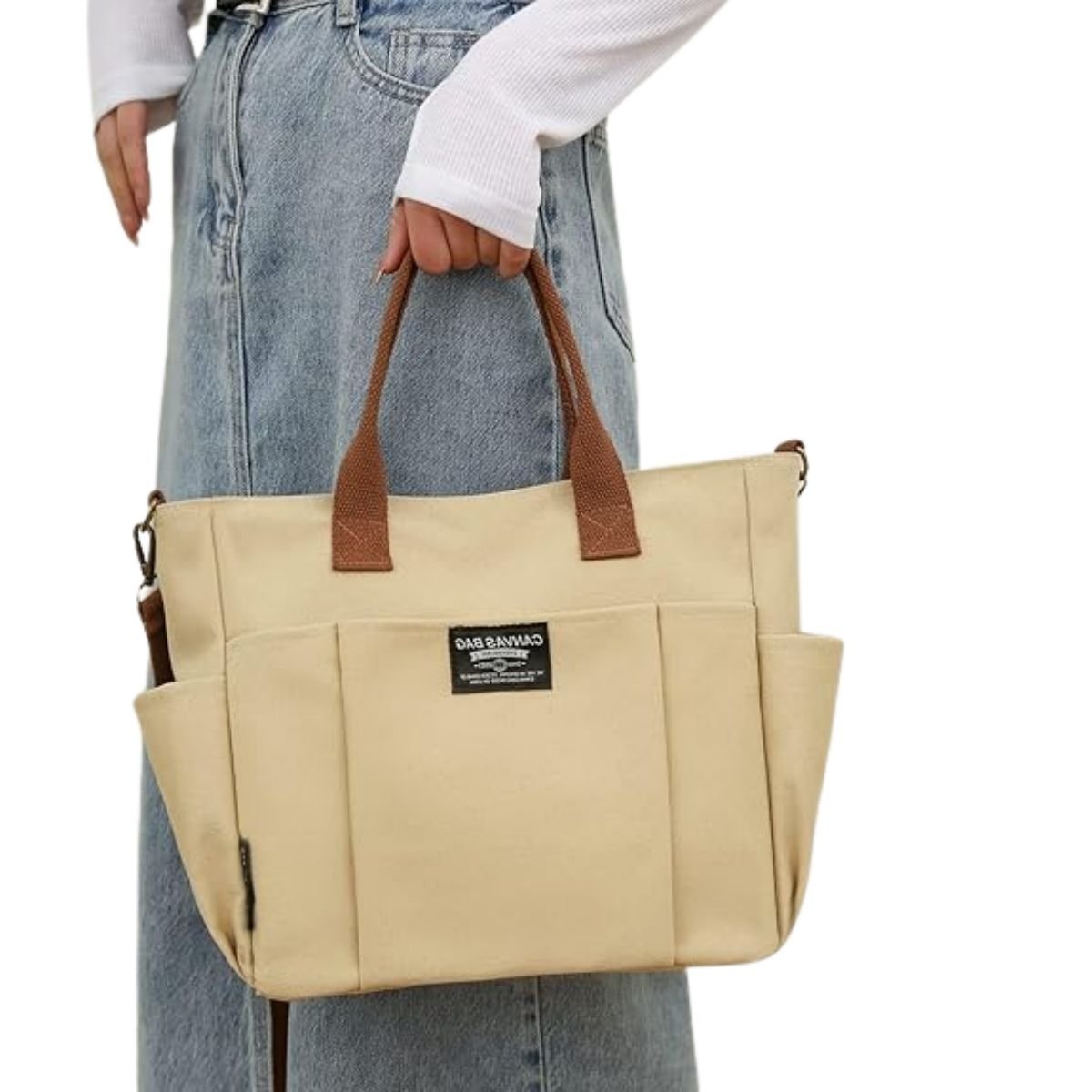 Sac a langer compact kaki porté à la main par une femme en jean, format compact élégant
