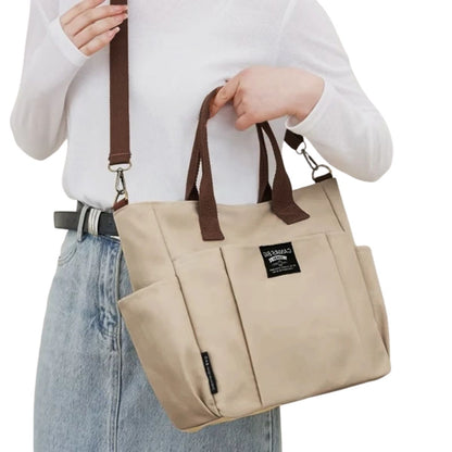 Sac a langer compact kaki porté en bandoulière par une femme, idéal pour sorties rapides