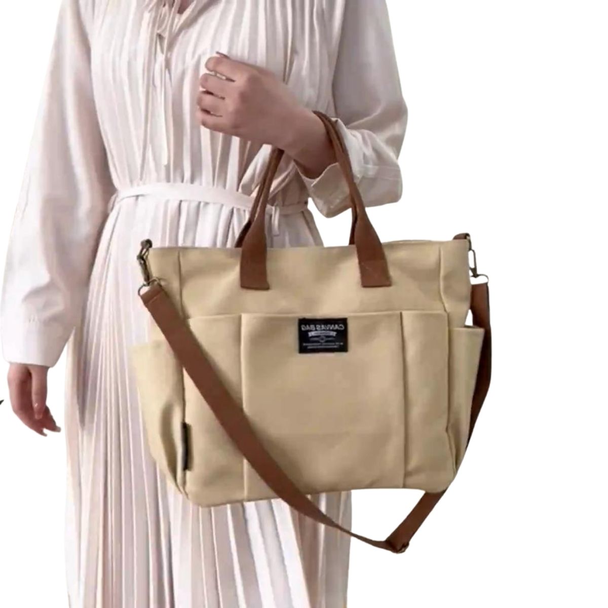 Sac a langer compact kaki tenu à la main par une femme en robe, poches latérales accessibles