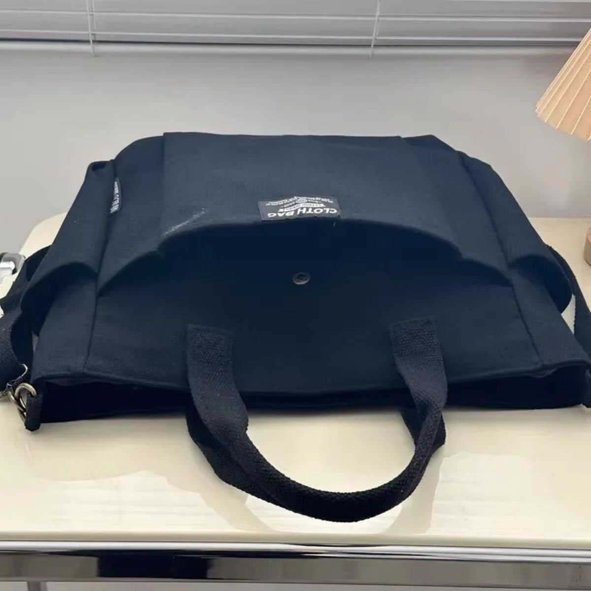 Sac a langer compact noir vu de dessous, toile rigide et anses résistantes visibles