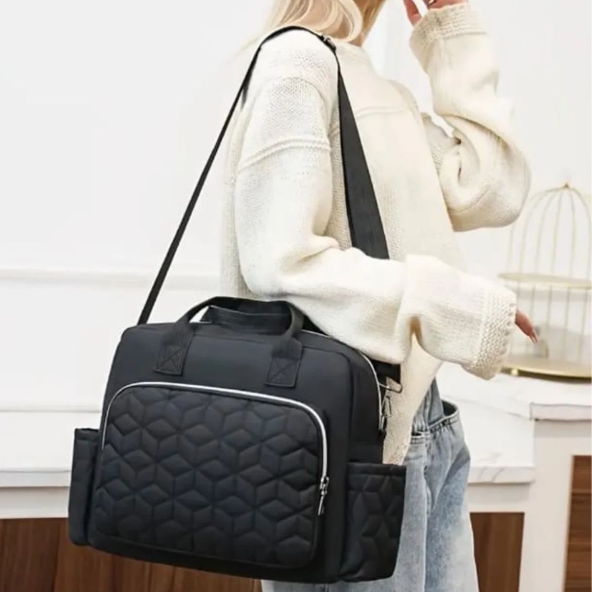 Sac a langer noir porté en bandoulière par une maman en tenue claire