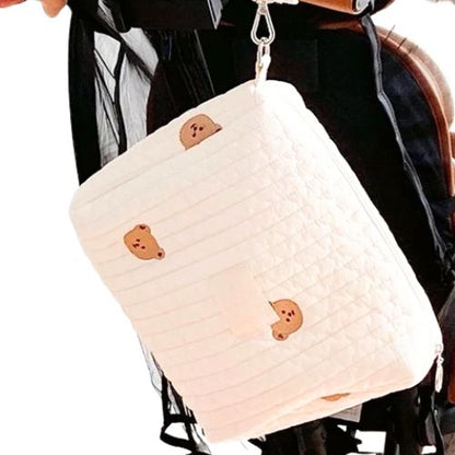 Sac a langer creme suspendu verticalement avec motif ourson vu de pres sur poussette.