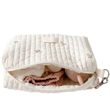 Sac a langer ouvert contenant un lange froisse, une couche et une tasse dans un interieur clair