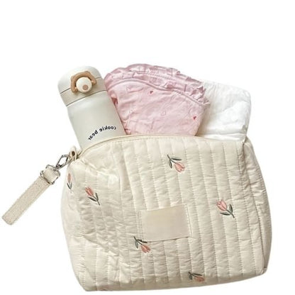 Sac a langer tulipe rempli avec biberon et lange rose pose sur fond blanc texture