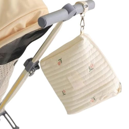Sac a langer tulipe suspendu a une poussette beige, vue laterale avec attache visible