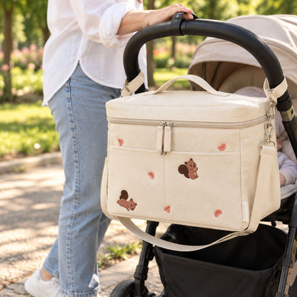 Sac à langer isotherme écureuil beige installé sur une poussette en extérieur