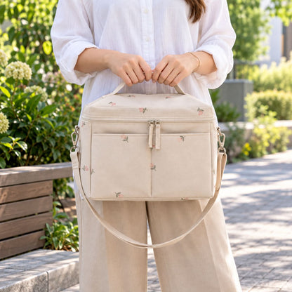 Sac à langer isotherme fleurs beige porté à la main en extérieur