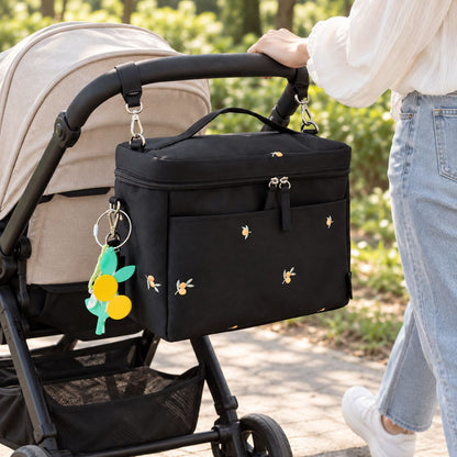 Sac à langer isotherme fruits noir installé sur une poussette en extérieur