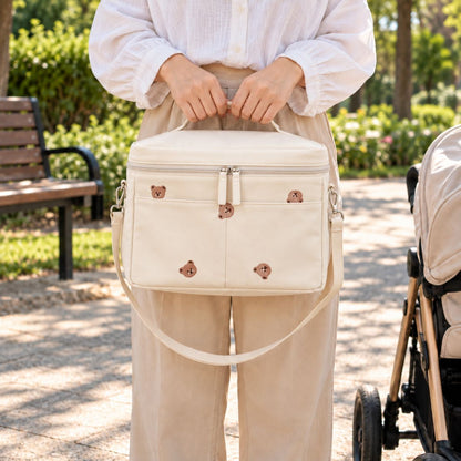 Sac à langer isotherme ours beige porté à la main en extérieur