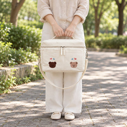 Sac à langer isotherme ours duo beige porté à la main en extérieur