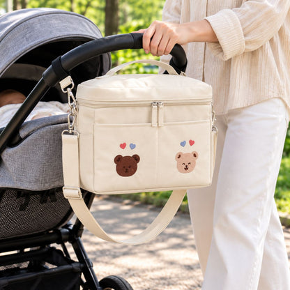 Sac à langer isotherme ours duo beige présenté près d’une poussette en extérieur