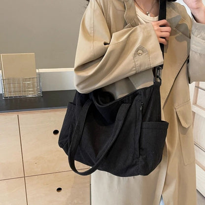 Sac à langer noir porté en bandoulière par une femme, modèle en tissu côtelé fonctionnel