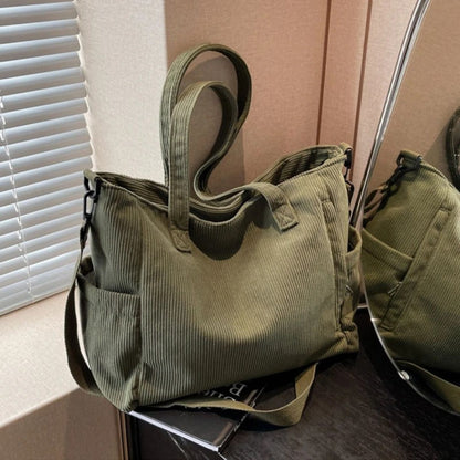 Sac à langer vert en tissu côtelé posé devant un miroir, format spacieux et élégant