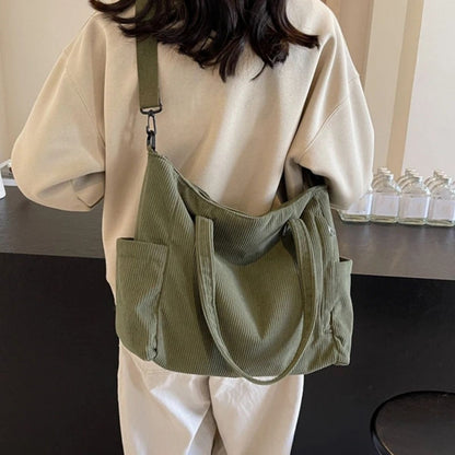Sac à langer vert porté au dos par une femme en intérieur, modèle confortable et fonctionnel
