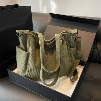 Sac à langer vert présenté dans une boîte, modèle en tissu côtelé avec anses et bandoulière