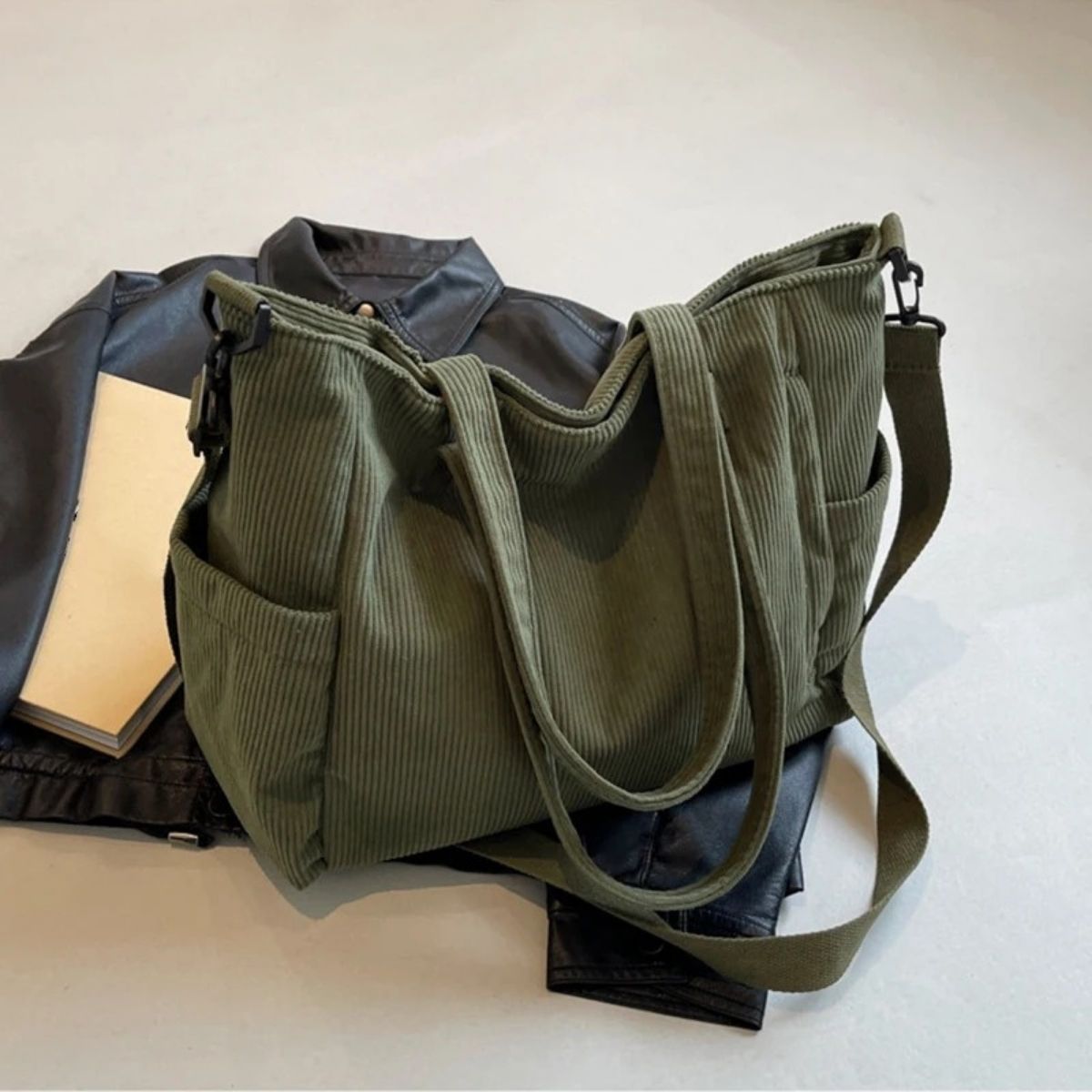 Sac à langer vert en tissu côtelé posé sur une veste, format équilibré et fonctionnel