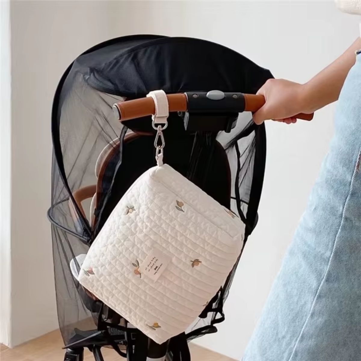 Sac à langer matelassé Petit Olive suspendu à une poussette avec son attache