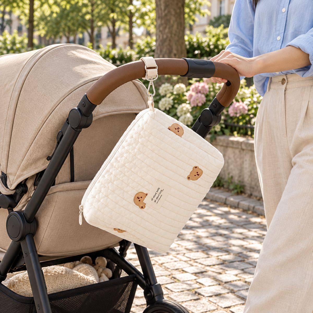 Sac à langer matelassé Petit Ourson suspendu à une poussette pendant une sortie en ville
